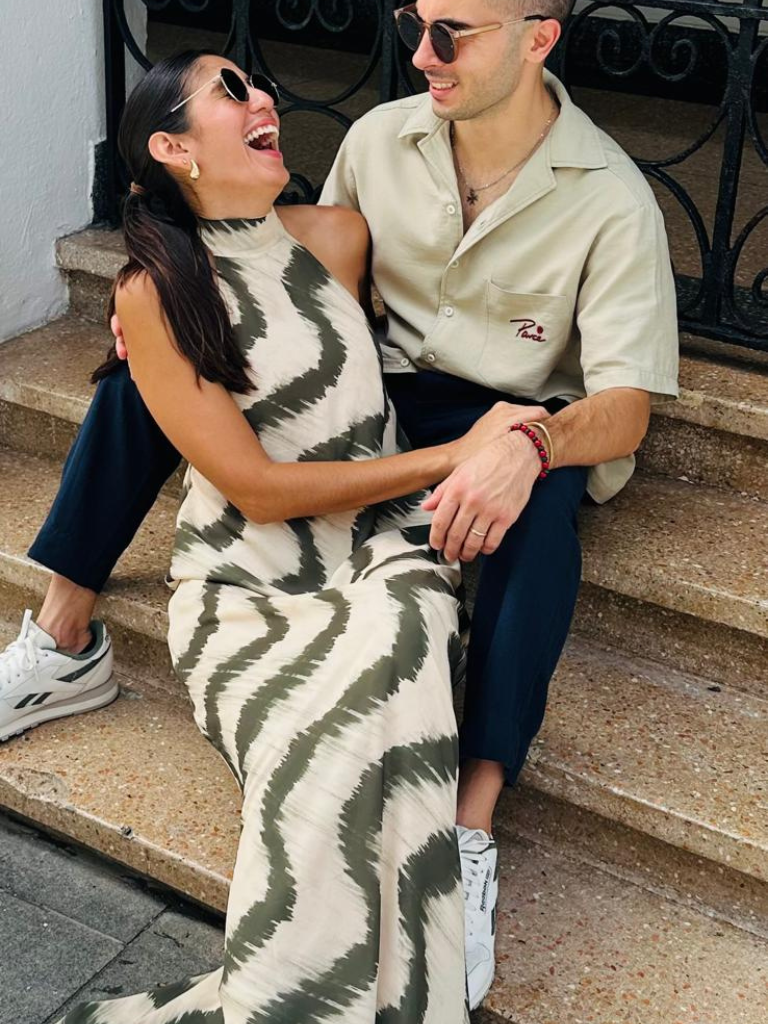 Close Up of model wearing the San Juan Maxi Dress by Parce Miami – sitting on a step, laughing with her partner