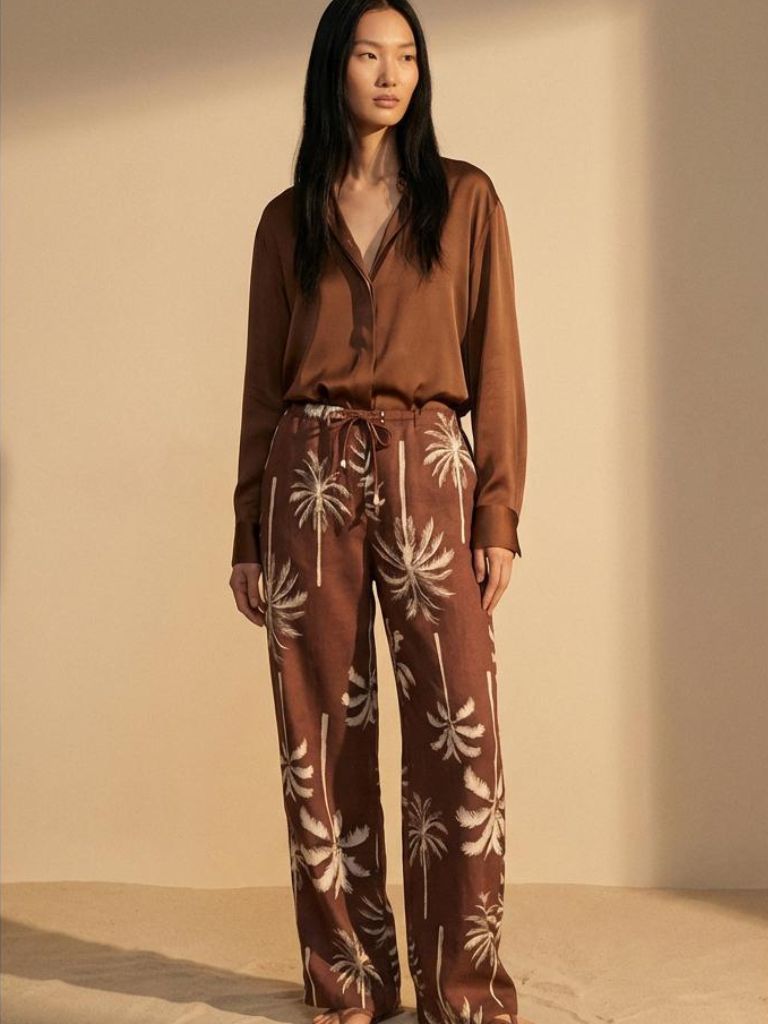 Woman wearing Coco Boogaloo Pant – cocoa-brown tropical pants with ivory palm print from the Salsa Lover Collection