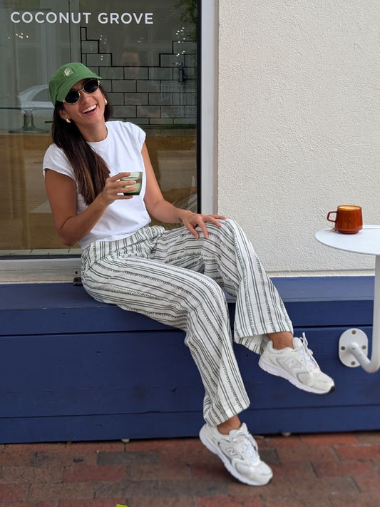 Woman wearing Parce Green Linen Pant sitting outside Coconut Grove café in relaxed resort outfit
