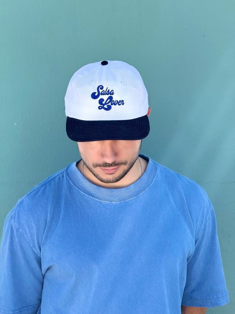 Person wearing a white cap with 'Salsa Lover' text against a green background