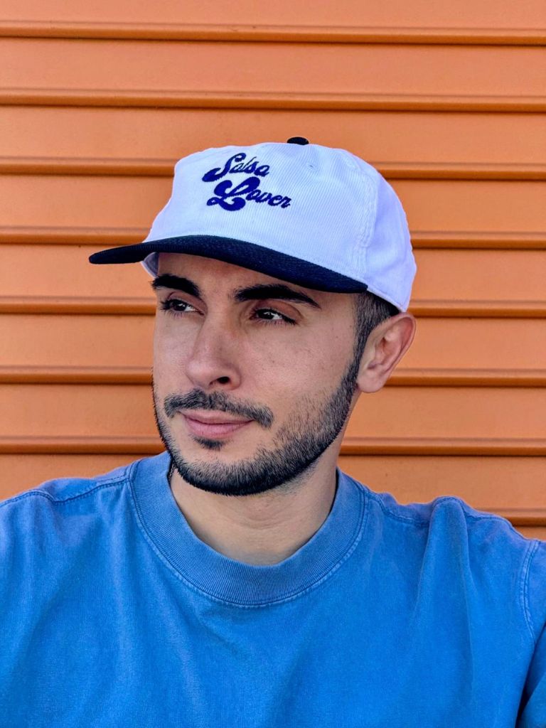 Man wearing a white cap with blue text against an orange background